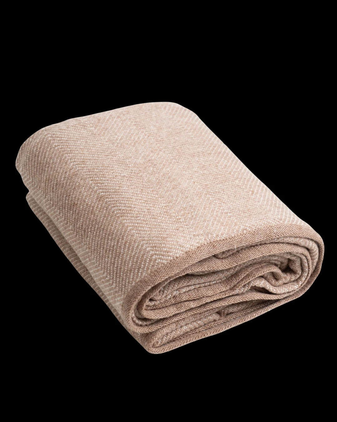 A folded cashmere throw in a soft camel herringbone weave